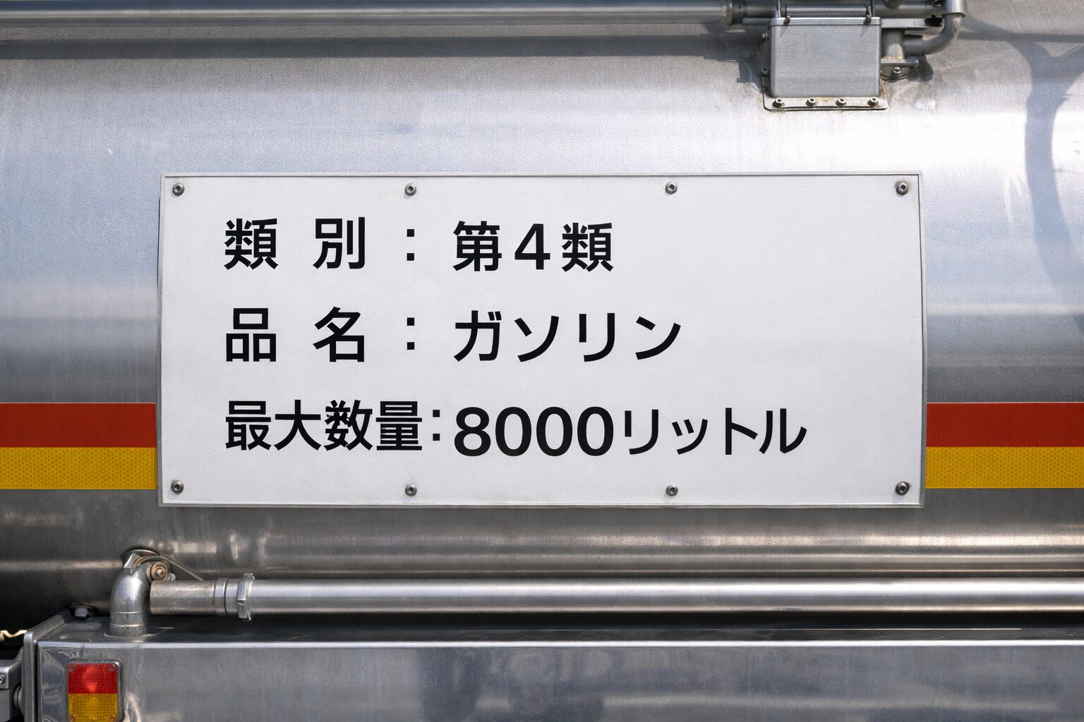 タンクローリー側面の掲示板。白地に黒文字で類別：第4類、品名：ガソリン、最大数量：8000リットルと記載
